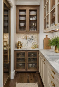 This elegant butler’s pantry features custom cabinetry with glass fronts, polished countertops, and vintage fixtures. It’s designed for functionality, with ample space for storing kitchen essentials and preparing food. #ButlersPantry #ElegantDesign #VintageStyle #LuxuryStorage #HomeOrganization