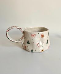 Enjoy the holiday and Christmas spirit while coming together with loved ones or sipping a warm drink on winter days. This handmade ceramic mug features a small world of, Christmas Ribbon, Christmas Tree Ornament, Gift Package, Candy Cane, Star, Christmas Tree, and Holly. The white color and meticulously crafted details make this mug a festive addition, creating a warm atmosphere during the holiday season. 📍The coaster in the first image will not be sent. 🎨 All of my ceramic items are designed,