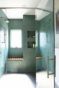 a large shower space clad with green stacked tiles, with niche shelves and a seat is a cool and stylish idea