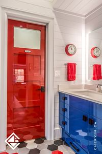 Bright and colourful kids' bathroom featuring a high gloss red door, blue vanity cabinets, and a tall blue built-in storage unit for all your kid's bathroom essentials. #KidsBathroom #HighGlossVanity #ModernDesign #BlueVanityCabinets #ColourfulBaths