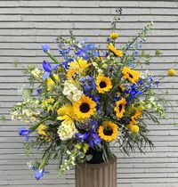 Part of our Artist Series, inspired by the works of Van Gogh, this showstopper of an arrangement features his signature sunflowers with elements of blue and purple in a quality ceramic container. An all around arrangement, this would make a great centerpiece for a foyer during an event or the entryway of your business!