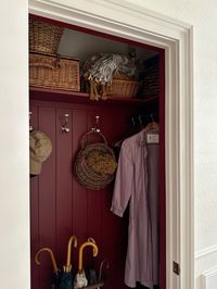 A moody hallway closet thats the perfect place to hang your coats, hats, umbrellas, and baskets for additional storage.