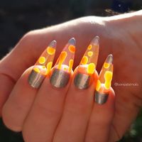 Lava lamp nails are the 70s-inspired manicure trend that's taking over Instagram right now. The trend turns long acrylic nails into mini lava lamps, complete with floating balls of lava. The design is based on aquarium nails.