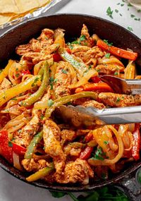 Chicken Fajitas in skillet with tongs