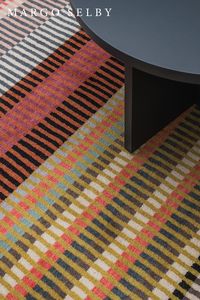 The Canterbury rug is a technically complex design achieved with 12 harmonious colours in a geometric progression. Chromatically subtle, in pinks, blues, ochres and olive, with a tonal range from black to ecru. The orthogonal linearity, narrow or broad, and regular or varying, makes for visual depth and interest.