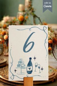 Hand painted watercolor wedding table number with hand drawn champagne wine and wedding cake illustrations. A quirky and fun addition to your wedding table stationery Shop my easy to edit canva templates today from Ashleigh Fish Paperie