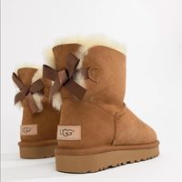 Brand New In Box Ugg Bailey Mini Bow Boots Ii. Size 9. Chestnut Brown Color. Perfect To Give As A Gift With Original Packaging And Box! Backed With A Ribbon Bow, The Bailey Bow Ii Boots From Ugg Are A Playful Take On Their Iconic Silhouette. Shaft Height: 6" Round-Toe Slip-On Boots Bow Detail At Back Water Resistant Suede And Stain Resistant Upper Pieced, Dyed Sheepskin Fur Upper 17 Mm Sheepskin Lining And Insole, And Treadlite Outsole For Comfort Sheepskin Upper; Wool Lining; Polyester Backi