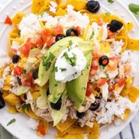 Over head shot of Mexican Haystacks on a white plate with a blue linen beside it.