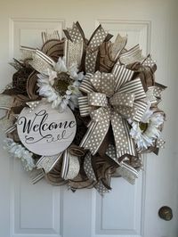 Handmade 24" Welcome Wreath with Beige and White Accents, Polka-Dot and Striped Ribbons, and White Flowers FREE SHIPPING IN THE UNITED STATES  Ready to ship.   Welcome guests to your home with this beautifully handcrafted 24" wreath. This elegant wreath features a charming "Welcome" sign, complemented by a delightful mix of beige and white polka-dot and striped ribbons. Adorned with lovely white flowers, this wreath is perfect for adding a touch of farmhouse charm to your front door. Details: -