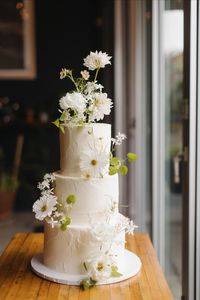 Styled cosmos dance across this textured cake. Gentle movement with delicate stems. Venue: The Whitechapel Projects | Photographer: Meg Dowd Photo | Florals: Brave Floral