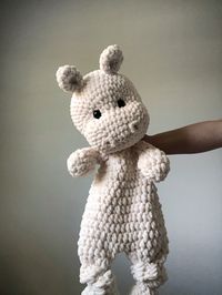 This super soft, plush and thick hand crocheted Hippo Snuggler will make the perfect addition to any nursery or kids room. Hand crocheted using bulky weight chenille yarn to create a super plush and squooshy Happy Hippo Friend for your Little. With a blanket body and stuffed head, this Happy Hippo is the perfect blend of blanket and toy.  The knotted legs make it easy for little hands to grip and hold, and it's large size makes it perfect for your special Little to snuggle with.   Color: Creamy