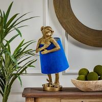 Funky monkey. This novelty lamp illuminates your space with an eclectic, maximalist vibe. It measures nearly 2' tall, and it's made from resin in a burnished gold hue and has a simple, circular base. The design features the shape of a cheeky monkey holding the lampshade around its middle like it's wearing a dress. We love that the class fabric shade comes in a luxe blue velvet for a pop of bright color. This table lamp plugs in with a standard cord and turns on with an in-line switch, and it tak