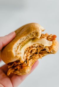 hand holding a chicken parmesan slider that has a bite out of it