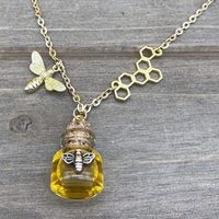 The delicate details of this gold bee themed dangle necklace are adorable. The honey bee dangle charm and a tiny pot of honey hang on a long adjustable 27"-29" chain. For additional style, the chain includes a delicate block of honeycomb. The lobster claw clasp and open loop design of the chain allow you to adjust it length as short as 16".