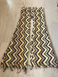 I thrifted this beautiful crochet, chevron blanket which I wanted to upcycle into bell-bottoms- so I gave it a shot! So I folded the blanket lengthwise and placed a pair of leatherette leggings over the fabric as a pattern. I traced along while widening the leg as I got closer to the bottom hem. Once the pattern was cut out, I sewed the pieces together (super easy!). I did this with a thick yellow yarn that was similar to the yellow of the pants- I also used a plastic large eye nee…