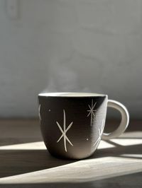 Discover the magic in everyday moments with this star-kissed mug. Generously sized and hand-crafted, it will become an essential part to your every day ritual , perfect for your morning brew or evening unwind. Its soft, earthy tones and delicate starry design invite a sense of calm and wonder. Let it be your companion for those serene sips of celestial energy. Listing is for 1 mug MEASURES :approx. 4" wide x 4" tall - Holds approximately 16oz Why You’ll Love It Dishwasher & Microwave safe Beauti