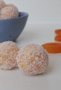 Close up of two apricot balls, behind them is more Apricot Balls sitting in a blue dish.