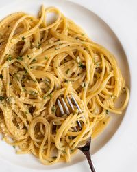 Spaghetti in a white wine butter sauce with parsley mixed through. A fork twirling into noodles.