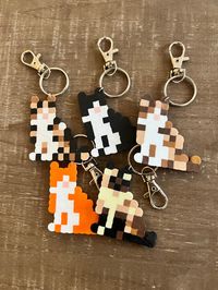 Custom Cat Perler Bead Keychains These handmade keychains are perfect for everyday bags and purses and go great with any backpack. They also make for a great gift for any cat parent!  How to order:  1. Select the breed/cat you want 2. Place your order  *If a custom order 3. Message me a photo of your pet 4. If there are any specific details about your pet you want me to add/know or other info you can message me as well Material: Perler Beads *Keychain can get wet