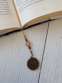 This item is not made until you order. Current processing is 2-3 weeks and takes into account the amount of orders ahead of yours.This beaded bookmark features a Czech glass bead portraying the enigmatic face of the man in the moon. It's adorned with a copper plated moon charm, adding a touch of the celestial to your reading experience. The boho wood mandala charm completes the look, providing a unique and artistic touch. Whether you're an avid book lover or looking for a thoughtful gift, this b