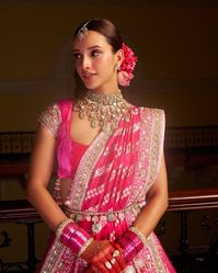 This exquisite pink bridal lehenga features intricate silver embroidery, adding a touch of sophistication and glamor. Paired with a heavy choker necklace, maang tikka, and bangles, the look exudes classic bridal elegance. The floral gajra in the hair bun complements the traditional vibe, making it perfect for weddings or grand celebrations. This ensemble is crafted for brides who adore a fusion of tradition and luxury. #PinkBridalLehenga #WeddingFashion #BridalOutfit #IndianBride #SilverEmbroidery #TraditionalBridalLook #ElegantEthnicWear #BridalJewelry #GlamorousBride #WeddingAttire