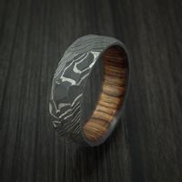 This 7mm Damascus Steel ring has a ROCK ACID finish and features a full WALNUT WOOD interior sleeve. Each ring is custom made and the pattern unique so no two rings are exactly the same. Damascus Steel rings are very desirable. You ring comes with a COMFORT-FIT for extra satisfaction. Our DAMASCUS ring WILL NOT RUST OR TARNISH. Damascus steel is an ancient art form. This blacksmith alloy is made using two types of Surgical and Fine Stainless steel that are layered in 100 alternating layer and th