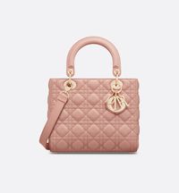 The Lady Dior bag epitomizes the House's vision of elegance and beauty. Sleek and refined, the timeless style is crafted in blush lambskin with Cannage stitching, creating the instantly recognizable quilted texture, while pale gold-finish metal D.I.O.R. charms offer elegant appeal. Featuring a thin, removable leather shoulder strap, the medium Lady Dior bag may be carried by hand or worn crossbody..