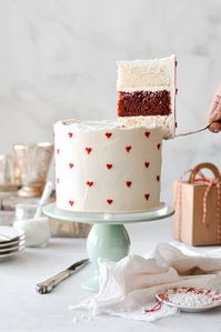 Striking layers of red and white velvet cake with pretty red buttercream hearts make a gorgeous cake for Valentines Day that everyone will love!