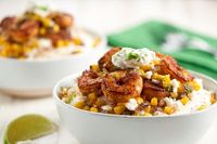 We've looked at infinite ways to remix the classic shrimp and grits into a new and exciting track that will top the charts. We've had some great hits, but this may be our favorite: a mash up with the popular Mexican flavors of _elotes_ (street corn). Roasted corn and onions and shrimp, flavored with smoky chili powder, top buttery grits. Served with lime crema and queso fresco, this meal is hitting all the right notes.