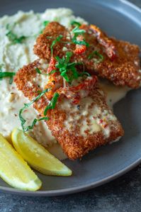 Finished dish of Parmesan-Crusted Tofu plated with lemon sauce, sundried tomatoes, and fresh basil