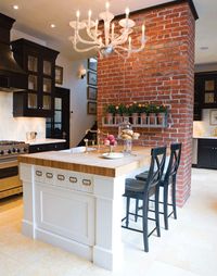 love the brick wall, the pretty chandelier and this amazing island with bar stools.