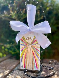 Hand painted textured angel Christmas ornament with white satin bow for hanging.  Colorful winged angel with metallic gold highlights. Wooden ornament measures approximately 3 1/4" x 6". This ornament will be a beautiful addition to your Christmas tree or can be displayed on its own using an ornament stand.