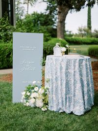 blue patterned cloth wedding, wedding table blue pattern, toile pattern table cloth, wedding cocktail table inspo, wedding welcome signage, blue wedding signage, white wedding florals, welcome table wedding, wedding cards box, guest book table wedding