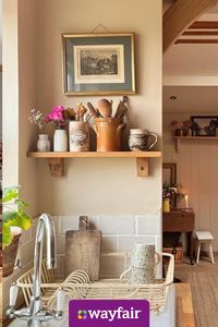 Give your sink space a rustic refresh with ceramic vases, wooden shelves, and gold-framed wall art.