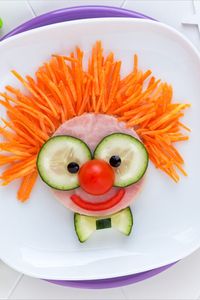 Eine tolle Karneval Frühstücksidee mit einem lächelnden Clown-Gesicht auf einem Schinken-Sandwich mit frischen Gurken, Karotten und Tomaten!