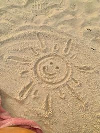 cute smiley sun design made in sand at beach, beach design