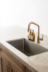 This stunning kitchen design features a sleek brushed brass faucet and a seamless stone countertop, blending style with functionality. Let DYM Builders bring elegance to your home! 🏡