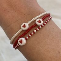 red and white seed bead bracelet with red heart bead strung on elastic please gently roll on and off to prolong its life handmade in venice, ca