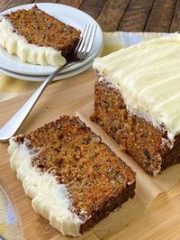 Carrot cake made in loaf pan on a cutting board next to slice on a plate