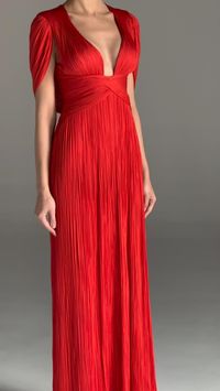 The LAUREL gown stands out due to the cinched waist and built-in cape that covers the shoulders, adding a touch of drama and majestic vibe to the overall appearance. The plunging neckline features a scalloped trim along the neckline, while the elegant column silhouette is a flattering choice that complements various body shapes.