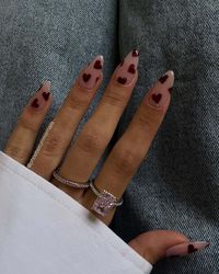 Experience the elegance of glossy burgundy hearts on a subdued backdrop, a bold expression of romance through nail art. Click to explore more of this passionate and sophisticated style.via@phoebesummernails