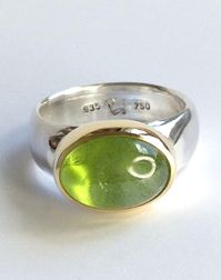 A magical peridot set in 18kt yellow gold on a 935 silver ring band. This beautiful peridot is a fresh spring green and has a wonderful vibrant look. The ring band tapers slightly towards the inside for a comfortable fit. In size 56 (inner diameter 17.8 mm), the ring is available immediately - for all other sizes, the specified shipping time applies. Size/Dimensions/Weight: Total weight: 11.4g Stone size: 14 x 10 mm / 8.6 ct. Ring band width: 8.2 - 6.2 mm Used material: peridot 935 silver 750 go