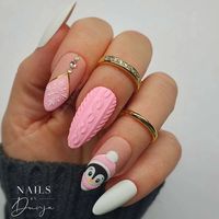 These nails showcase a delightful mix of textures and designs, including a soft pink base with a cable knit pattern, a cute penguin illustration, and a single matte white accent nail. Intrigued? Click to explore more of these playful nail designs.via@nails_by_dunjahabssaoui