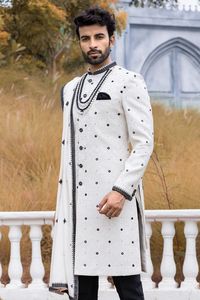 Experience the pure elegance, this raw silk white and black sherwani is a timeless classic and complemented by embroidery, mirror work, makes this a perfect choice for the groom who desires a regal yet refined appearance. Complete the ensemble with the matching chudidar and dupatta for a look the charm and grace.