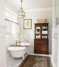 Vintage glass-front chest adds charm along with cafe curtains and claw footed tub.