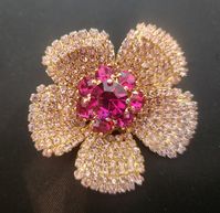 It's beautful this brooch/pin is made by weiss.and it signed on back. it's adorned with pinkish crystals on the leaves, and 7 med size ruby sets around a large center ruby crystal set. they all are prong set, very well made and looks like new. it's a gold tone in color. it measures 2'' round. i love this beautiful brooch/pin, but i have to sell all my pretty's.a collector would it.                                                                                                        my stock #