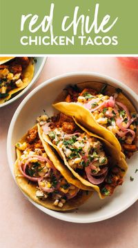 These Red Chile Chicken Tacos are always on our minds! Lightly pan-fried corn tortillas stuffed with tender chicken and a pinto bean red chile saucy filling, piles of creamy corn salsa, and tangy homemade pickled red onions. YUM! #chicken #taco #redchile