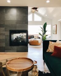 Spacious rustic mid-century haven, complete with walnut tones and brass + charcoal accents. This pop of green sofa adds a little contrast and color to this space. The three-sided fireplace is the main feature of this room. #openconcept #interiordesign #homedecor #remodel #renovation #rustic #midcentury #mcm #livingroomremodel #rustichome #sofa #livingroom #interiordesign #color #homedecor #rustic #livingroom #modern #fireplace