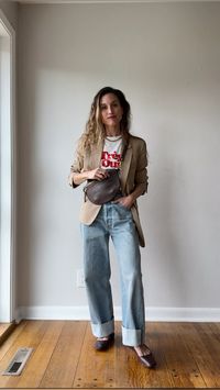 Casual chic spring outfit idea with a camel blazer, graphic tee, baggy cuffed jeans, and ballet flats