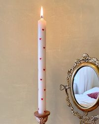 Candles have always been popular for adding a sense of coziness to a room. Our Hand Painted Heart Candle is perfect for adding a little more interest to your living space or dining area. These soft and delicate essentials are not only good to light and cozy up your space, they are also very decorative. The perfect mix of fun and color, this candle is adorned with red hearts, painted by hand. Mix and match with our candle holders for the ultimate vibe. We also love it paired with our Floral Print